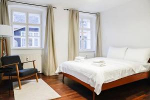 Authentic Austrian Flat in the South of Vienna في مودلينغ: غرفة نوم بسرير وكرسي ونوافذ اثنين