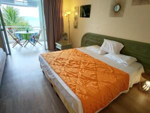a bedroom with a large bed with an orange blanket at Studio vue mer, pieds dans l'eau in Le Gosier