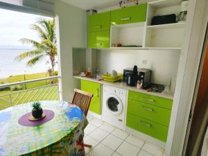 a kitchen with green cabinets and a washing machine at Studio vue mer, pieds dans l'eau in Le Gosier