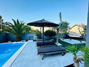 a pool with chairs and an umbrella next to a pool at Apartmani Vernissage in Biograd na Moru