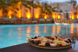 a plate of food and wine glasses next to a pool at Q Alaçatı Luxury Hotel in Cesme