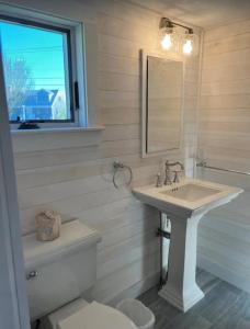 ein Badezimmer mit Waschbecken, Toilette und Spiegel in der Unterkunft Charming Cottage with Amazing Views in Truro + 13 Fotos