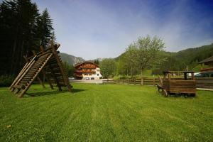a grassy yard with a wooden playground and a building at Steinerhof in Braies