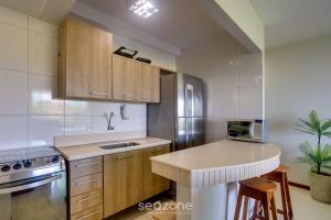a kitchen with wooden cabinets and a counter top at Apto vista p/ rio c/ varanda - Pontal BCL402 in Ilhéus