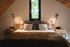 a bedroom with a bed with pillows and a window at Bérc Kabin Kismaros in Kismaros