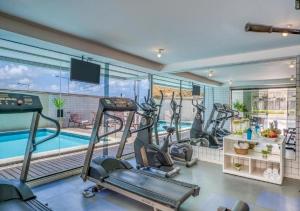 a gym with cardio equipment and a swimming pool at Golden Tower - Flat a Beira Mar in Natal