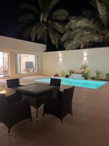 a patio with a table and chairs and a pool at Cove Chalet 1شاليه كوڤ in Al Ahsa