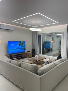 a living room with a large couch and a tv at Cove Chalet 1شاليه كوڤ in Al Ahsa