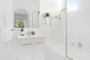a white bathroom with a shower and a sink at Urban Oasis Prahran in Melbourne