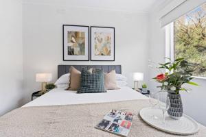 a white bedroom with a large bed and a window at Urban Oasis Prahran in Melbourne