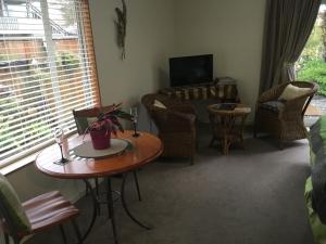 a living room with a table and chairs and a television at Park view Greenmeadows Napier in Napier