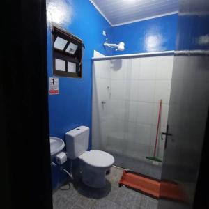 a blue bathroom with a toilet and a shower at Tahoma Chalé Rustico Verde Prumirim in Ubatuba