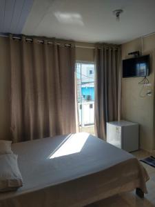 Pousada Nhá Chica في ساو ثومي داس ليتراس: غرفة نوم بسرير كبير ونافذة