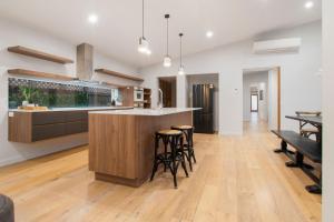 an open kitchen and living room with a bar and stools at Thorne St Luxe Loft - CBD Location, Modern Design in Wagga Wagga