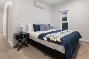a bedroom with a bed with a blue blanket and a window at Thorne St Luxe Loft - CBD Location, Modern Design in Wagga Wagga