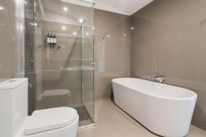 a bathroom with a tub and a toilet and a shower at Thorne St Luxe Loft - CBD Location, Modern Design in Wagga Wagga +19 photos
