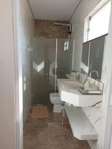 a bathroom with two sinks and a toilet and a shower at Lindo Loft no centro de Assis in Assis