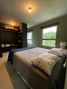 a bedroom with a large bed with a window at Apartamento praia brava in Itajaí +16 photos