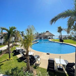 une piscine avec des chaises, des tables et des palmiers dans l'établissement Depa Coral con Club de Playa Exclusivo Playa Bonfil Diamante, à Acapulco