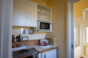 a small kitchen with a microwave and a stove at Quince Cottage - scenic escape with spa in Daylesford
