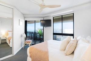 a bedroom with a white bed and a balcony at By The Beach - Clubb Coolum Beachside Resort in Coolum Beach
