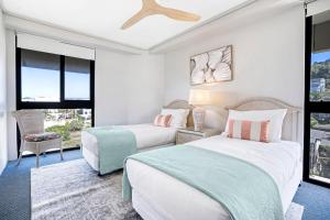 two beds in a room with two windows at By The Beach - Clubb Coolum Beachside Resort in Coolum Beach