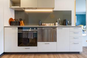 a kitchen with white cabinets and an oven at Stadium Walk Apartment - City Centre and Parking in Christchurch