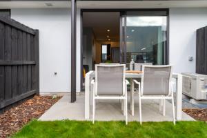 a white dining table and chairs on a patio at Stadium Walk Apartment - City Centre and Parking in Christchurch +35 photos