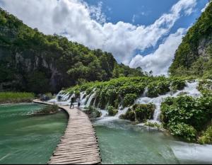 a wooden bridge over a river with waterfalls at Anamarija Apartments in Ličko Petrovo Selo