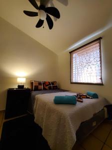 Un dormitorio con una cama con ventilador de techo y una ventana. en Kokys Guest House, en Nueva San Salvador