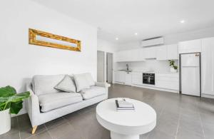 a white living room with a white couch and a table at Studio 37 Byron Bay in Byron Bay