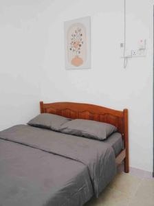 a bed in a white room with a wooden headboard at Trio homestay Bandar Kuala Terengganu in Kuala Terengganu