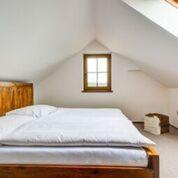 a white bedroom with a bed with a window at Ranč Kostelany in Kroměříž