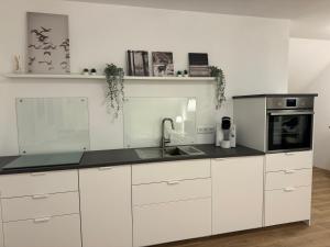 a white kitchen with white cabinets and a sink at Ferienwohnung Auf Der Höll in Daubach