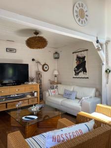 a living room with a white couch and a tv at Villa avec piscine au bassin d'Arcachon in Gujan-Mestras