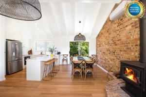 an open kitchen and living room with a brick wall at Anacapri - Pet Friendly - Opposite Beach - Fireplace in Callala Beach