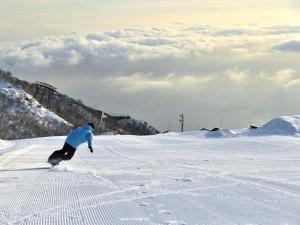 a man riding a snowboard down a snow covered slope at Lake Biwa Otsu Prince Hotel in Otsu