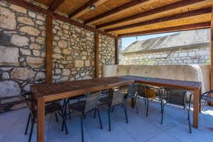 a wooden table and chairs in a room with a stone wall at Casa Royal in Bribir