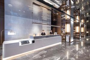 two people sitting at a counter in a lobby at Atour Hotel Guangzhou Baiyun Station Julong Metro Station in Guangzhou