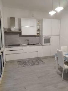 a kitchen with white cabinets and a sink and a table at Villetta Le Cesine in Torre Specchia Ruggeri