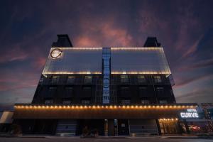 un edificio con un reloj encima por la noche en Curve Hotel Iksan, en Iksan