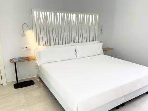 a large white bed in a room with a side table at Feelathome Rivero Apartments in Seville
