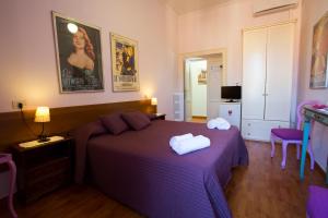 1 dormitorio con 1 cama morada y 2 toallas en Laterano Inn, en Roma