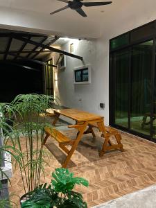 a wooden picnic table in a room with plants at Homestay Senggarang in Senggarang