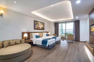 a hotel room with two beds and a couch at Gonsala Hotel Nha Trang in Nha Trang
