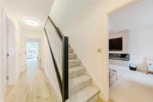 a staircase in a white house with a tv at Cheshire home by Chelsea in Macclesfield