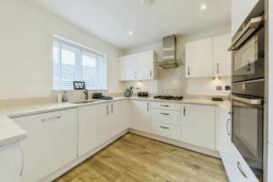 a white kitchen with white cabinets and a wooden floor at Cheshire home by Chelsea in Macclesfield