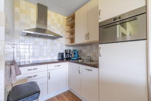 a kitchen with white cabinets and a refrigerator at Appartementencomplex Juliana 102 in De Koog