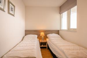 two beds in a room with a table and a window at Appartementencomplex Juliana 102 in De Koog +3 photos