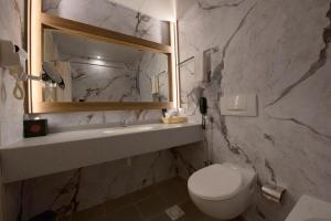 un bagno con un water, un lavandino e uno specchio di Ramee Guestline Hotel a Mascate